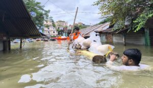 Young men in Feni, Bangladesh moving possessions during heavy flooding. YouthNet for Climate Justice - Bangladesh